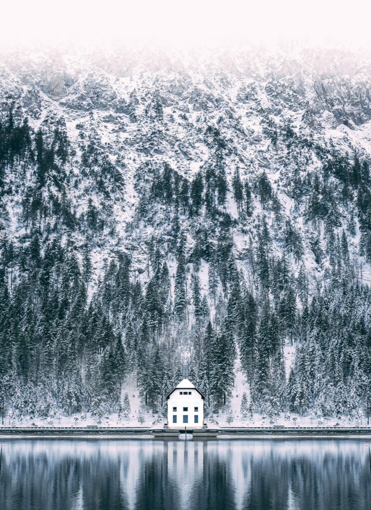 White house by icy lake reflecting snowy forest and frosty mountain winter landscape wallpaper