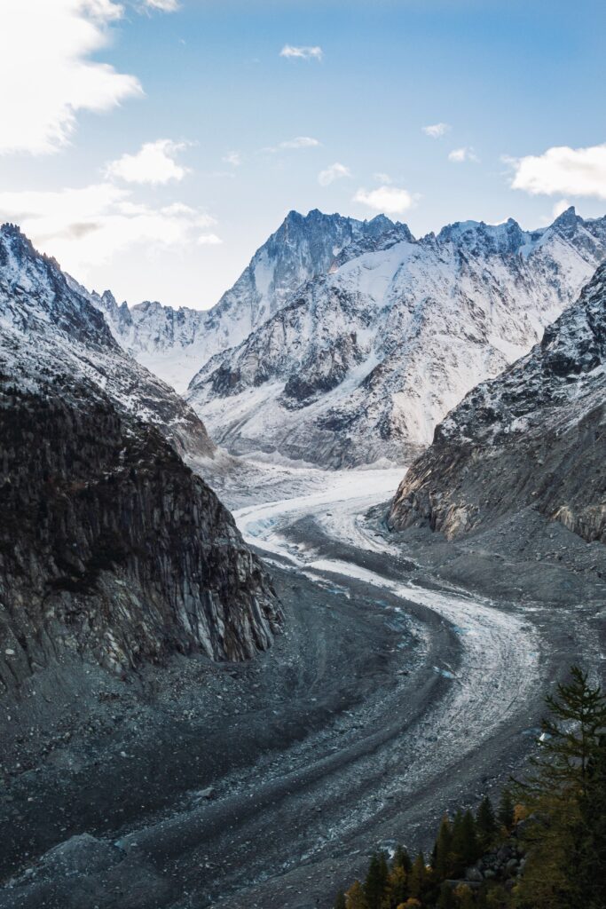 Aerial view of winding road through snow-dusted rugged mountains and icy winter valley landscape Wallpaper