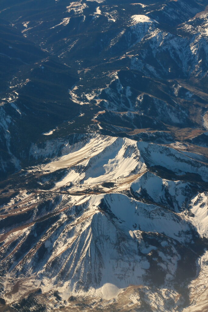 Snow-capped mountain peaks with rugged terrain and deep shadows in a winter wilderness wallpaper