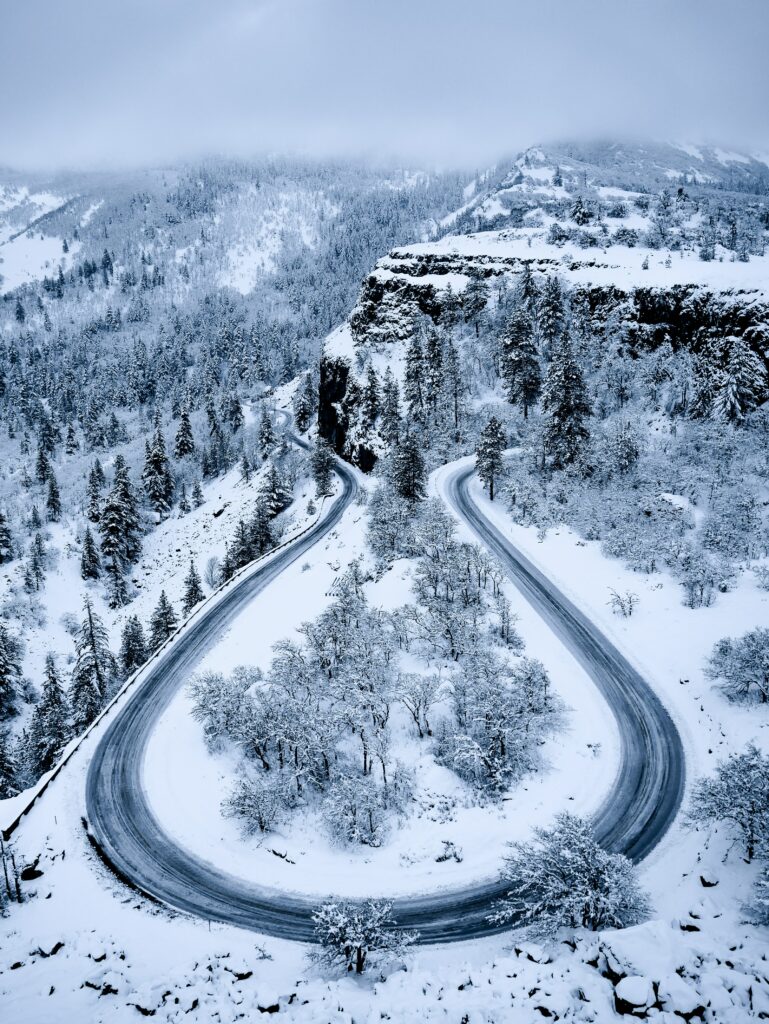 Aerial view of winding road through snow-covered mountains and frosted winter forests landscape Wallpaper