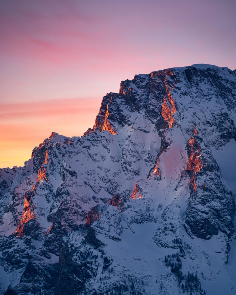 Winter mountain landscape with snow-covered rocks bathed in warm sunset hues wallpaper