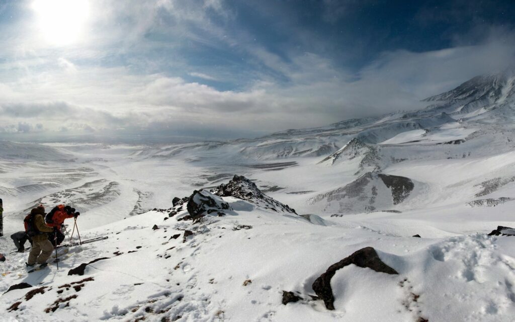 Mountaineers trekking snowy peak winter landscape with dramatic sky adventurous mountain wallpaper
