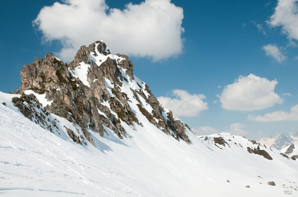 Rugged rock formation rising from snow-covered landscape under clear blue winter sky wallpaper