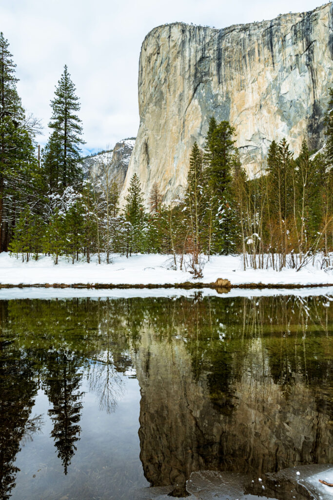 Winter river with snowy banks pine trees and rocky cliffs reflecting clear water landscape wallpaper