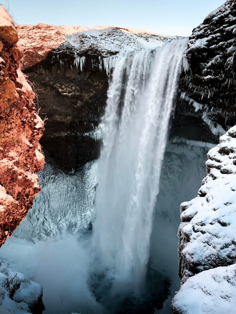 Winter waterfall cascading over snowy cliffs with icy pool serene natural landscape wallpaper