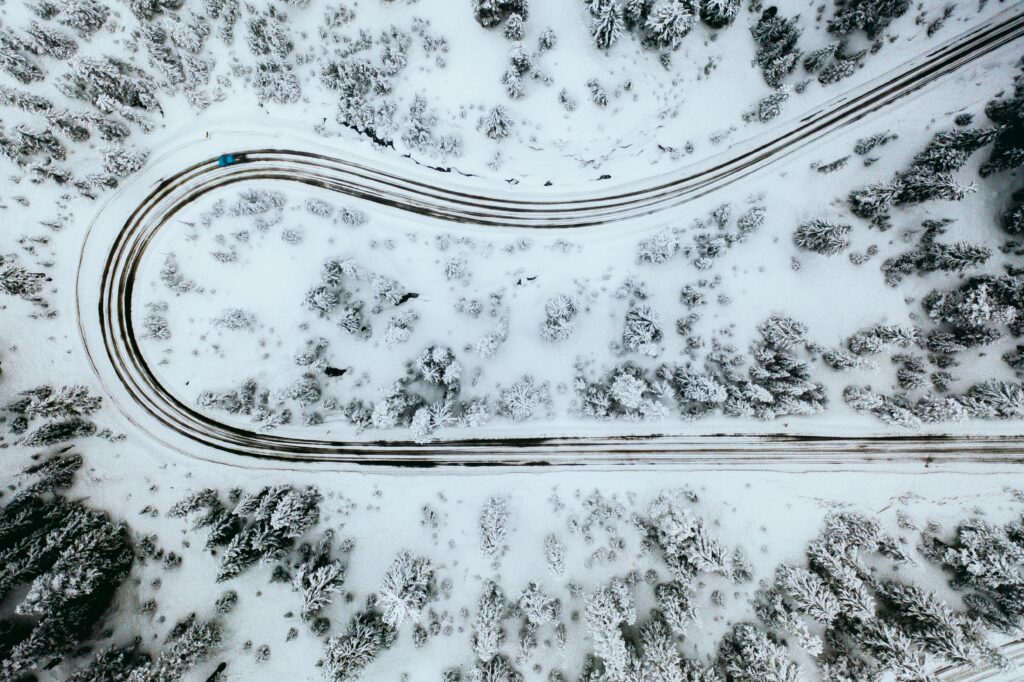 Top view of winding snowy road through frosted trees winter landscape wallpaper background
