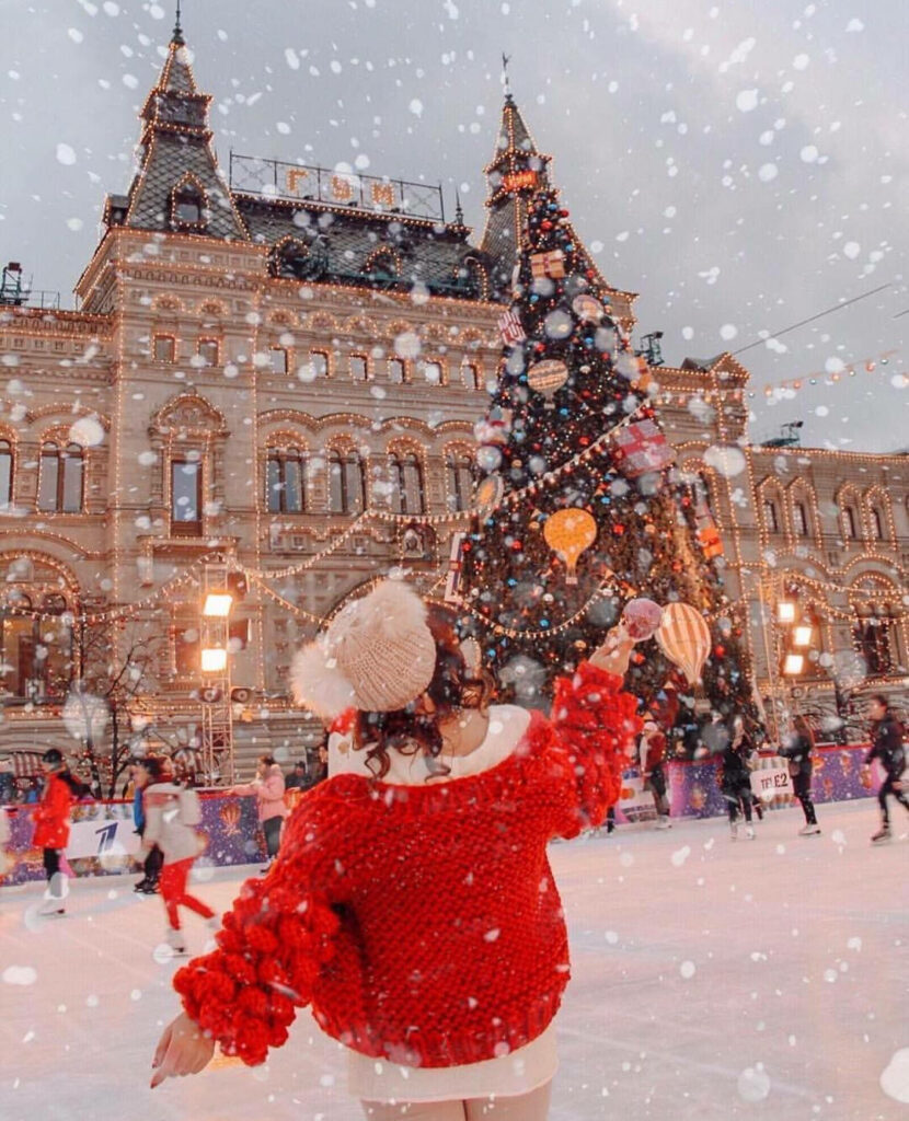 Winter Wonderland: Enchanting Yuletide Delights Surround Girl in Festive Attire amid Snowfall and Majestic Christmas Tree Wallpaper