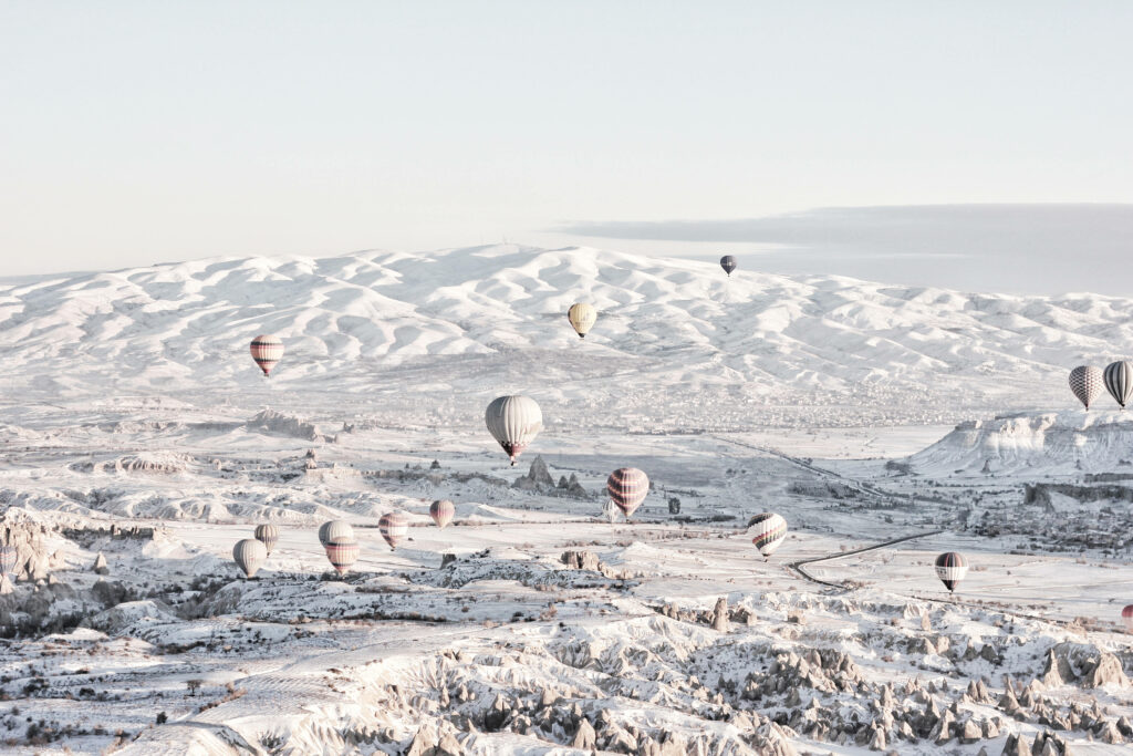Winter Wonderland: Majestic Turkish Mountains and Enchanting Hot Air Balloons Wallpaper