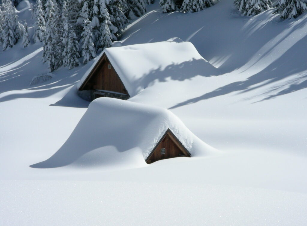 Snowy Retreat: Two Cozy Brown Huts Blanketed in Snowfall - Wallpaper