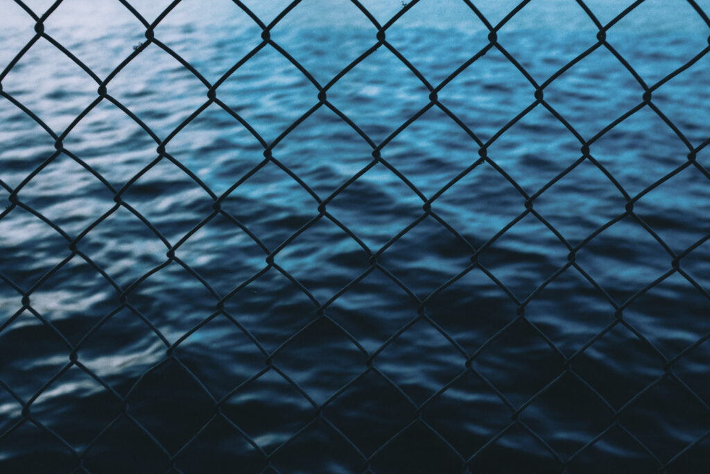 Close-up wire fence with deep blue sea background calm wallpaper with geometric and natural contrast
