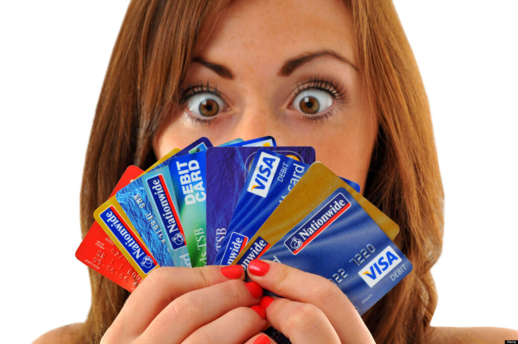Woman with wide eyes holding colorful credit and debit cards showing financial options and choices Wallpaper