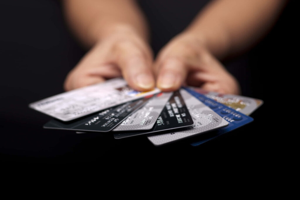 Hands holding multiple credit cards fanned out highlighting finance and modern consumer choices Wallpaper