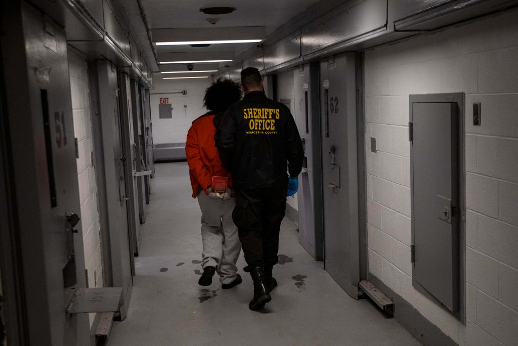Worcester County Sheriff escorting handcuffed inmate through bleak prison corridor wallpaper background