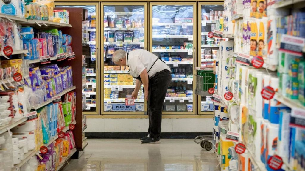 Grocery store worker restocking refrigerated display aisle daily retail supermarket scene wallpaper