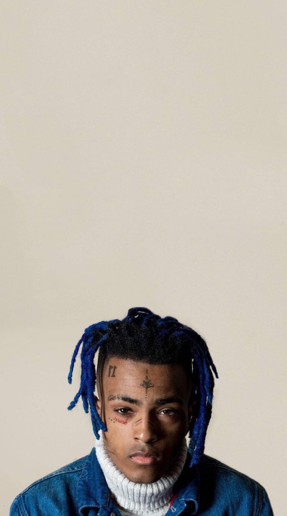 Studio portrait of rapper XXXTentacion with vibrant blue dreadlocks and facial tattoos wallpaper