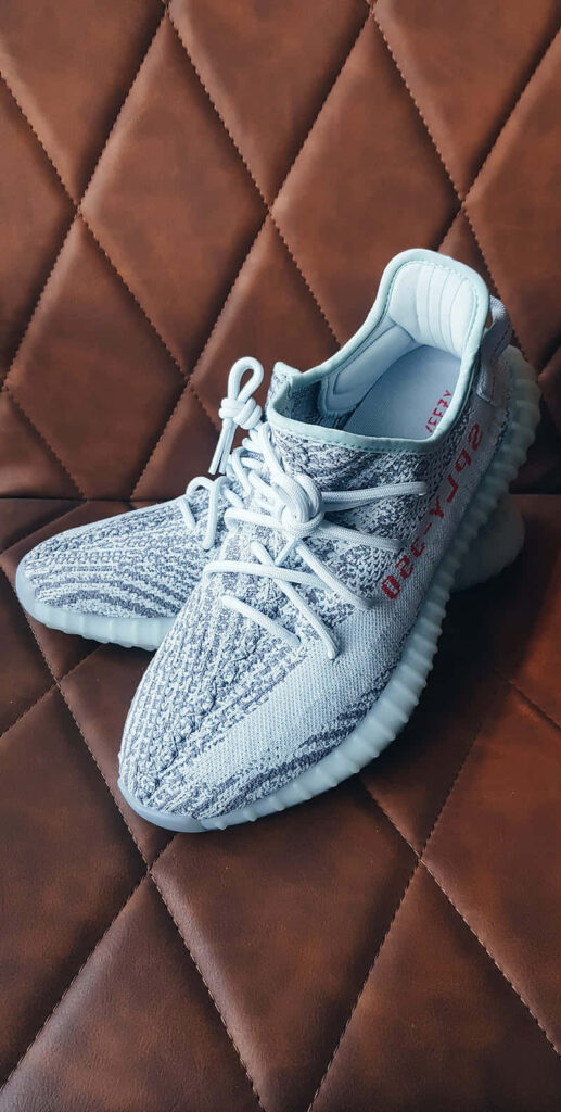 Stylish Yeezy sneakers on textured brown background showcasing iconic YEEZY design appeal Wallpaper