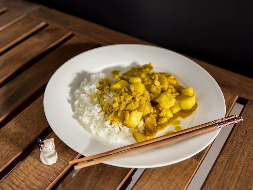 Delicious Yellow Curry with Rice on Wood Surface – Cat Decor Wallpaper