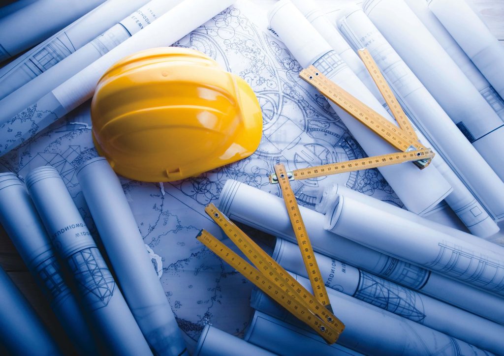 High angle view of yellow hard hat blueprints and wooden ruler construction workspace background Wallpaper