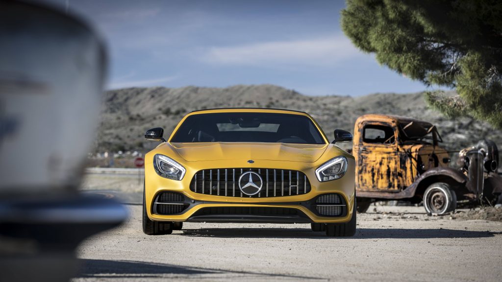 Yellow Mercedes AMG GT R supercar beside rusted vintage truck in arid landscape wallpaper