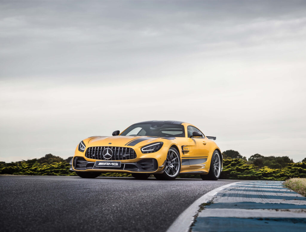 Yellow Mercedes Benz AMG GT R low angle on racetrack aggressive sporty design overcast sky Wallpaper