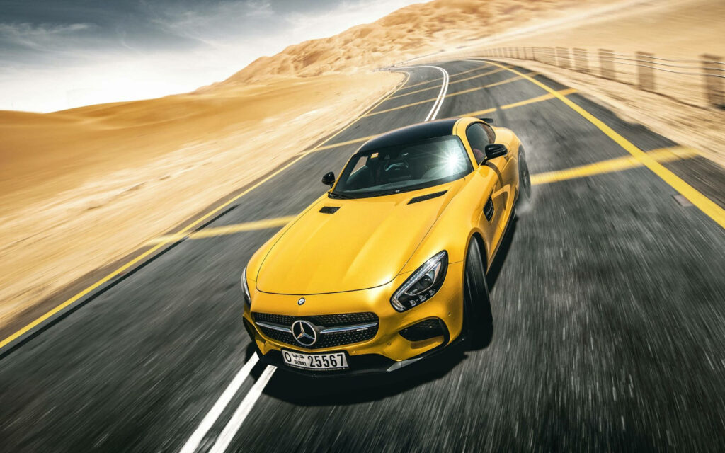 Yellow Mercedes-Benz sports car speeding on desert highway under clear blue sky wallpaper background