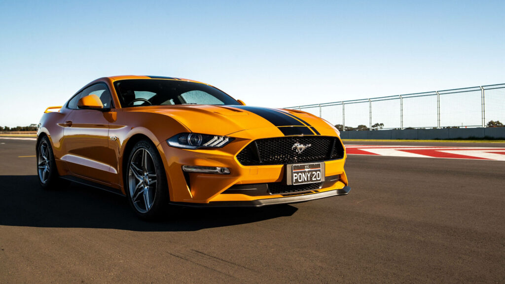 Yellow Mustang GT with black racing stripes parked on racetrack in sharp 4K Ultra HD detail Wallpaper