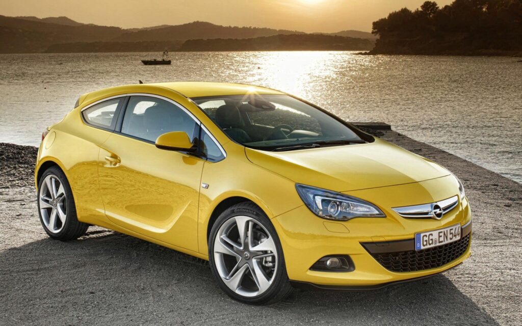 Striking Yellow Opel Astra GTC at Sunset by Calm Waterfront Wallpaper