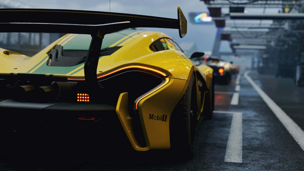 Yellow aerodynamic race car parked on wet track under overcast sky dynamic racing wallpaper