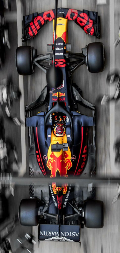 Yellow and red Formula 1 car racing fast through pit lane aerial view dynamic racing wallpaper