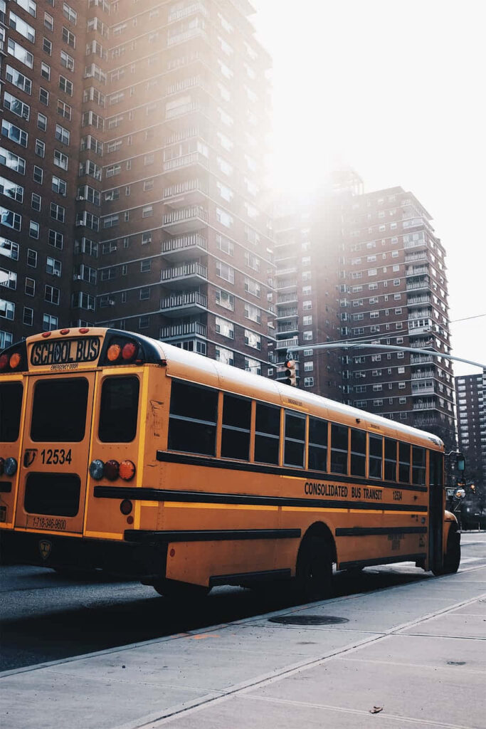 Sunlit Yellow School Bus Wallpaper in Urban Cityscape