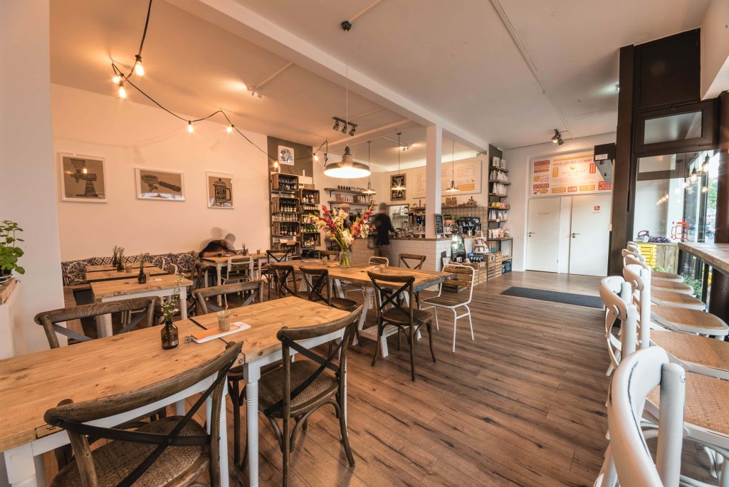 Minimalist YellowBird Coffee cafe interior with warm string lights and rustic wooden tables wallpaper