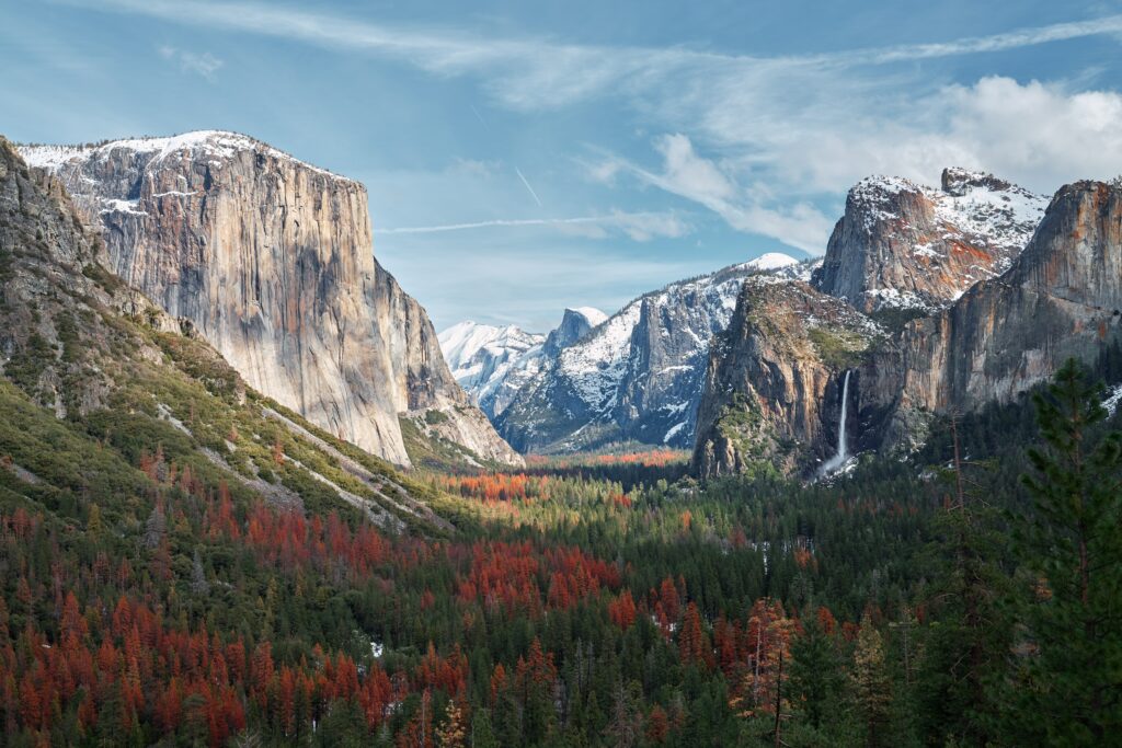 Yosemite Valley wallpaper with granite cliffs lush forests vibrant trees and snow-capped peaks