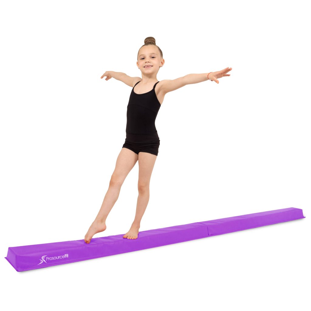 Young gymnast in black leotard balancing on purple ProsourceFit beam in bright studio Wallpaper