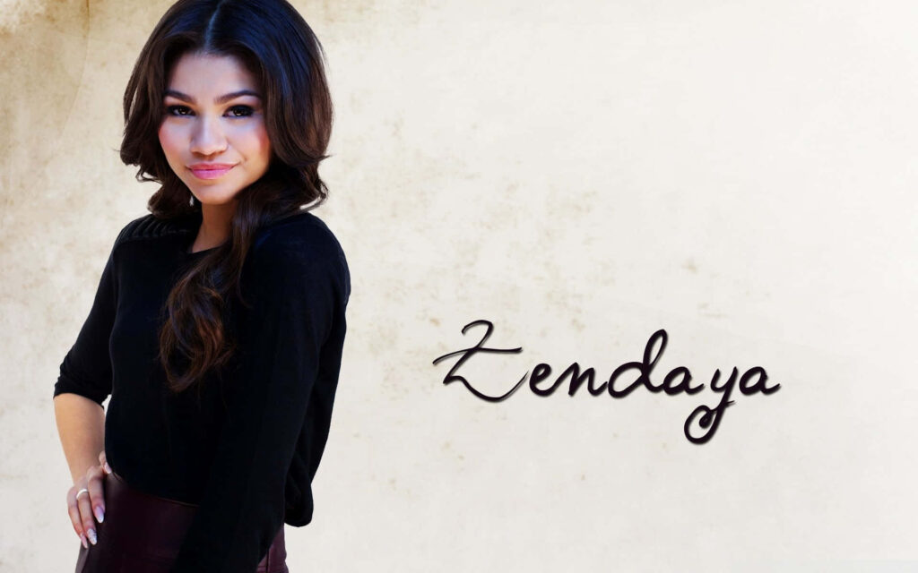 Zendaya confident pose minimal light background stylish black cursive name wallpaper design