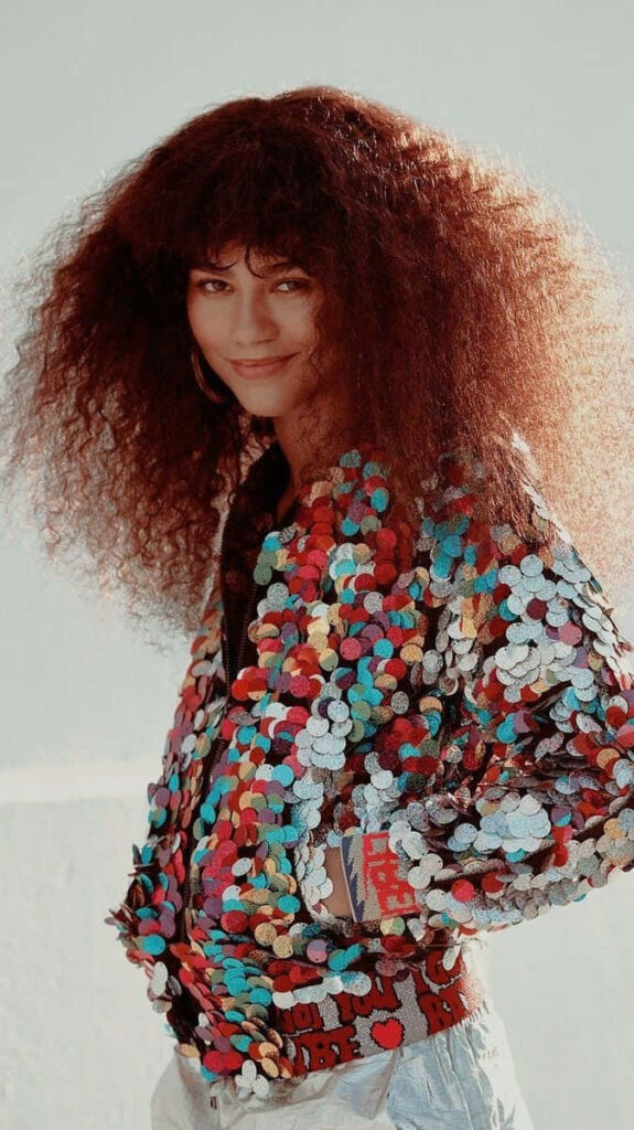 Zendaya with voluminous afro hair wearing colorful sequin jacket vibrant HD wallpaper background