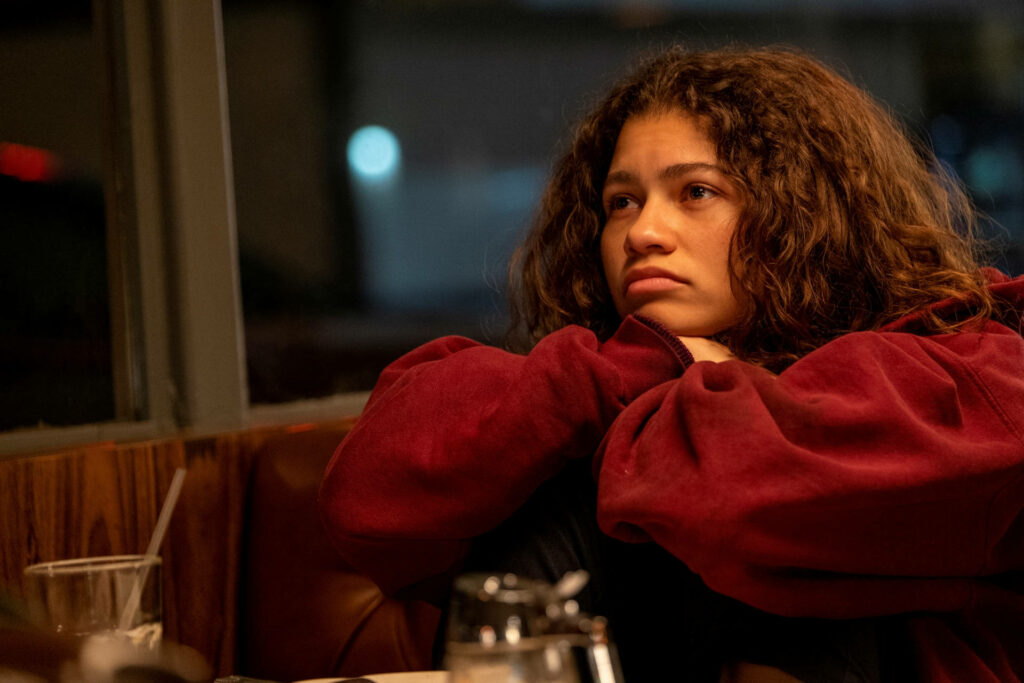 Zendaya as Rue from Euphoria in red sweater thoughtful diner scene emotional series wallpaper