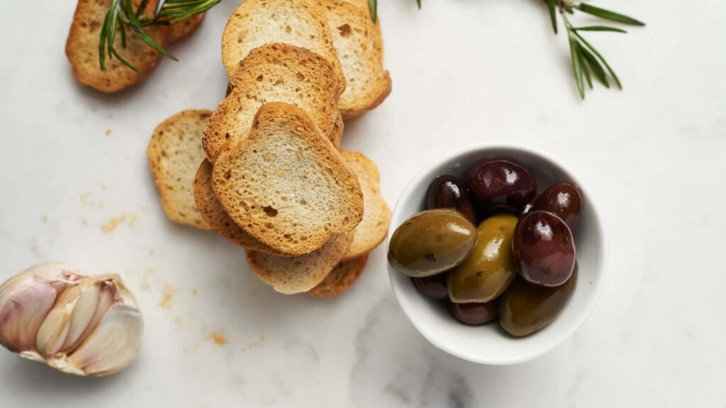 Rustic toasted bread with green and black olives fresh rosemary garlic Mediterranean food background Wallpaper