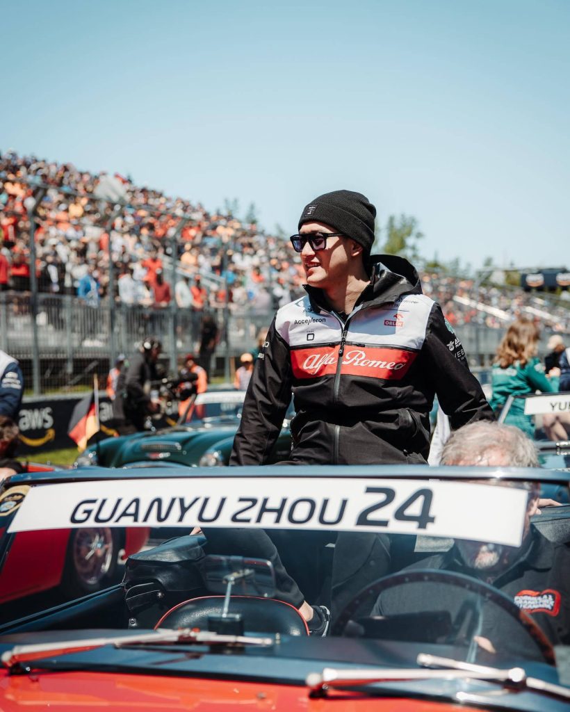 Formula 1 driver Zhou Guanyu in Alfa Romeo jacket during sunny drivers parade at racetrack Wallpaper
