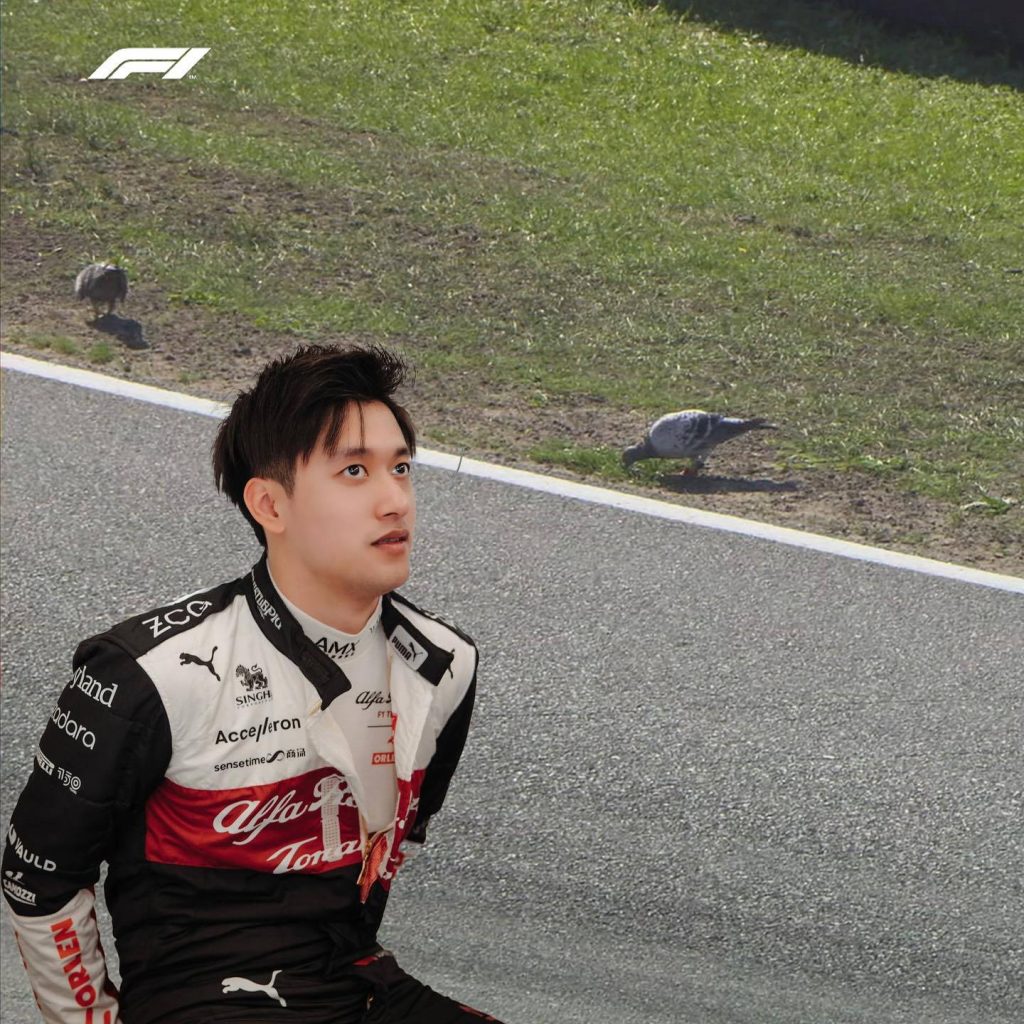 F1 driver Zhou Guanyu in Alfa Romeo suit thoughtful trackside with pigeons motorsport wallpaper