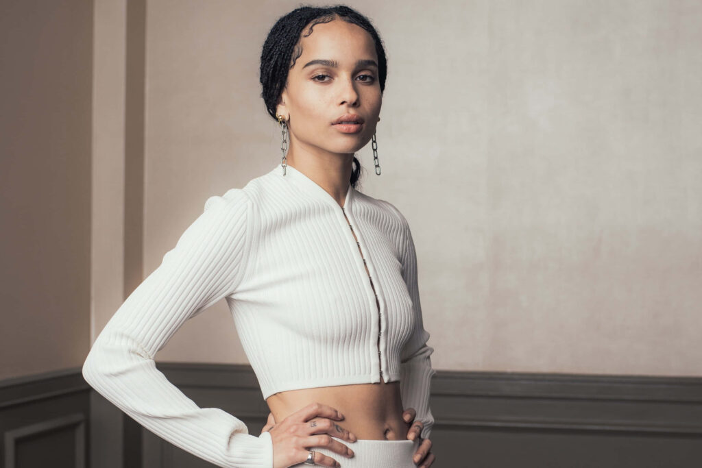 Zoë Kravitz in elegant ribbed white top confident pose neutral background sophisticated portrait Wallpaper