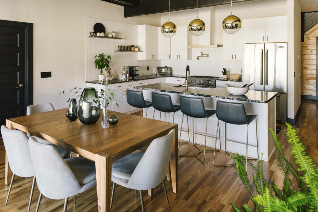 Modern kitchen Zoom background with white cabinets marble island gold lights and wooden dining set Wallpaper