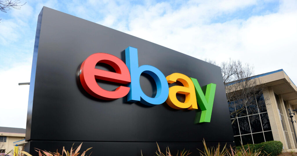eBay logo in colorful letters on black sign outside modern office building under bright sky Wallpaper