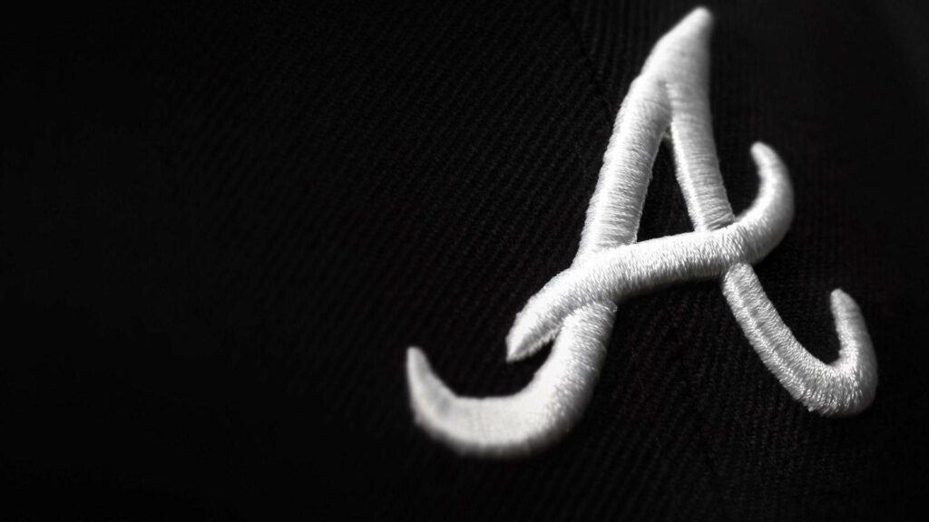 Atlanta Braves cursive A logo white embroidery on black fabric detailed macro wallpaper background