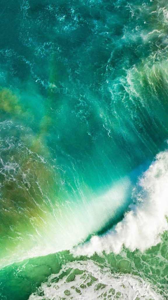 iOS 9 default wallpaper showing vibrant turquoise ocean wave crashing with white foam background