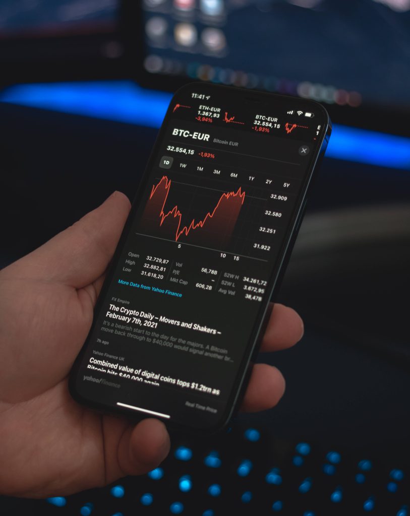Close-up of iPhone showing Bitcoin chart on Yahoo Finance app with blue-lit keyboard background Wallpaper