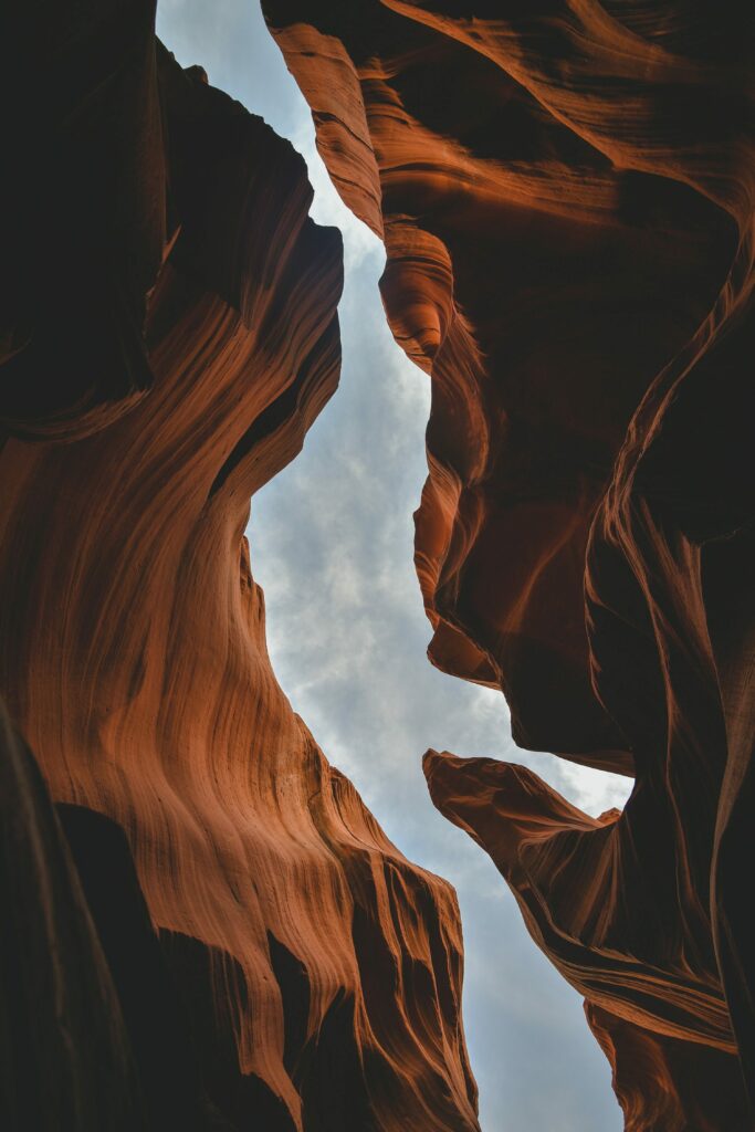 Dramatic reddish canyon rock formations under soft cloudy sky scenic natural wallpaper background